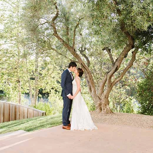 Wedding couple kissing under trees at the CIA at Copia, in Napa, CA.